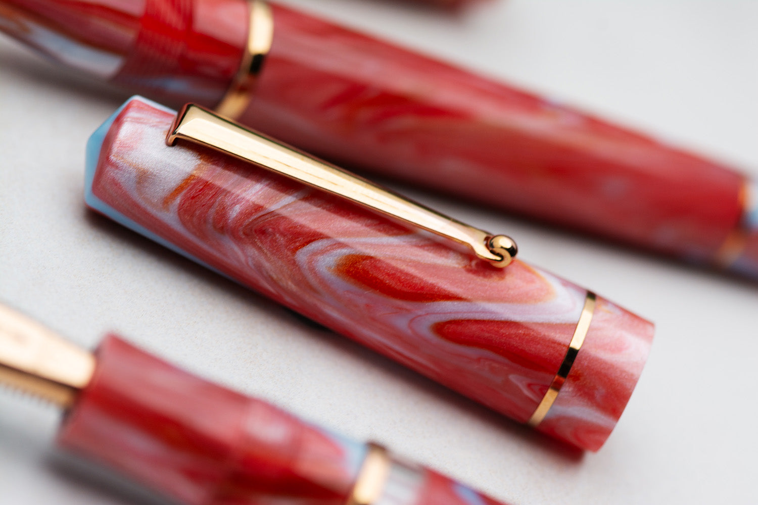 Marbled red and white pen with gold accents on a light background Delta Duna Ghibli Red Fountain Pen cap detail 2 made in Italy