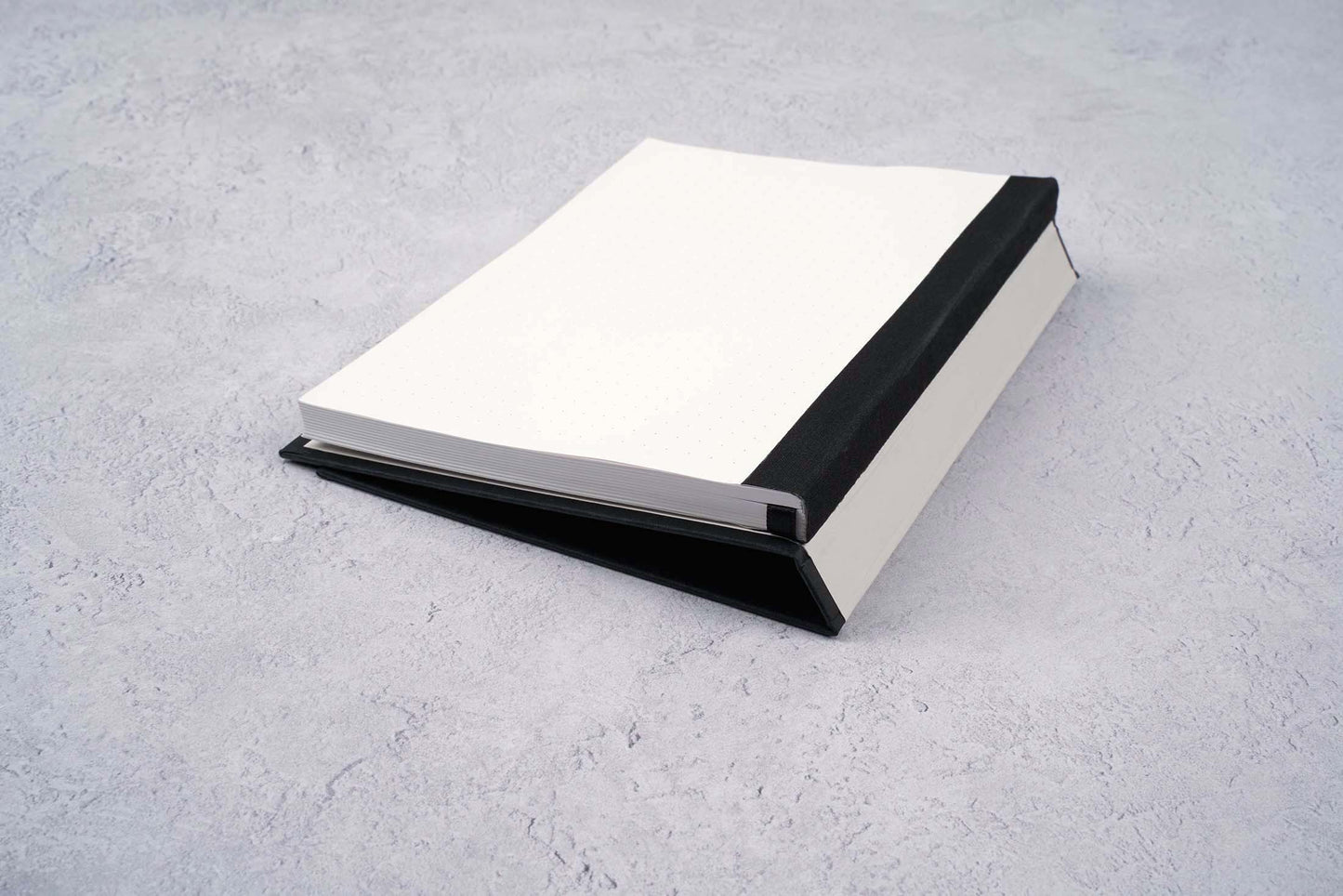 black blocker paper notebook showing off the Swiss binding and dot grid pages. cover is folded over to show the ultra flexible design of this fountain pen friendly notebook