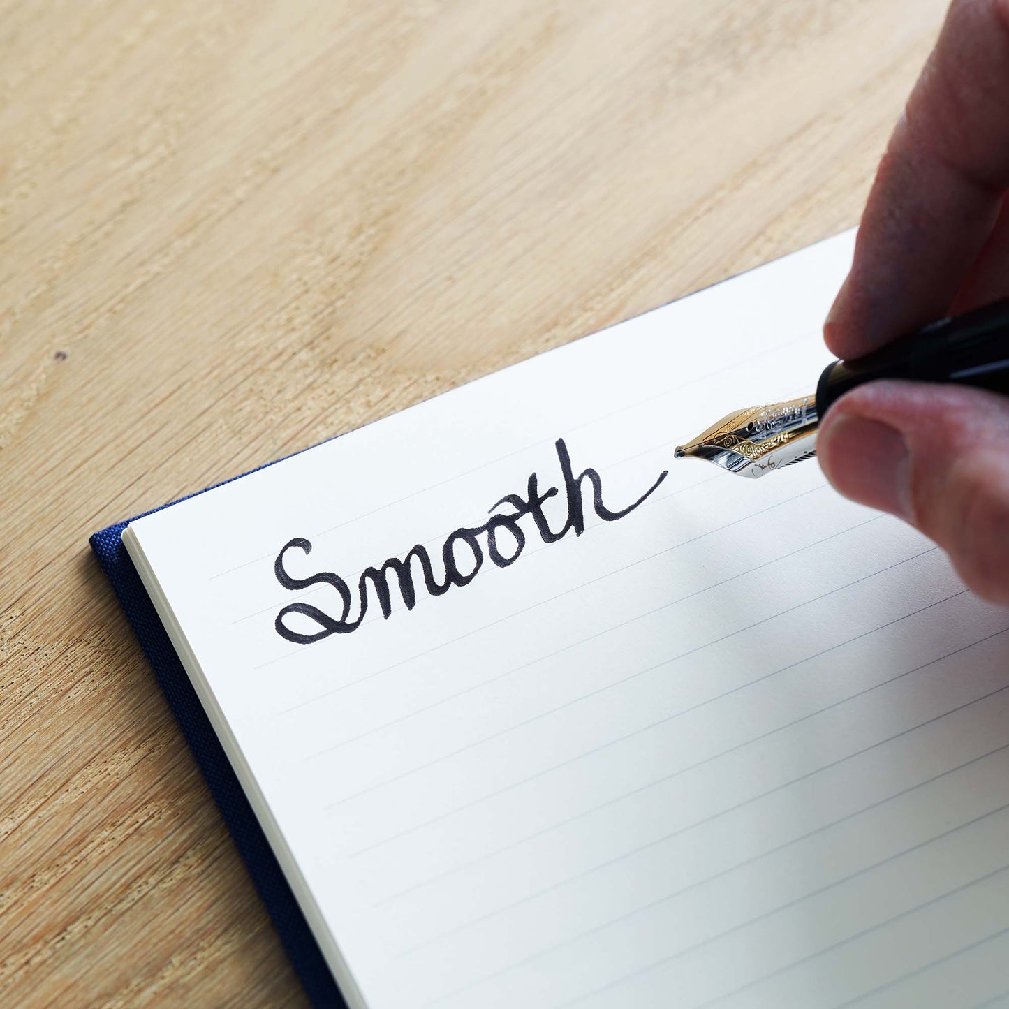 The Paper Mind Passepied Cream Hardcover Notebook with the word Smooth written on it with a Montblanc 149 fountain pen on an oak desk