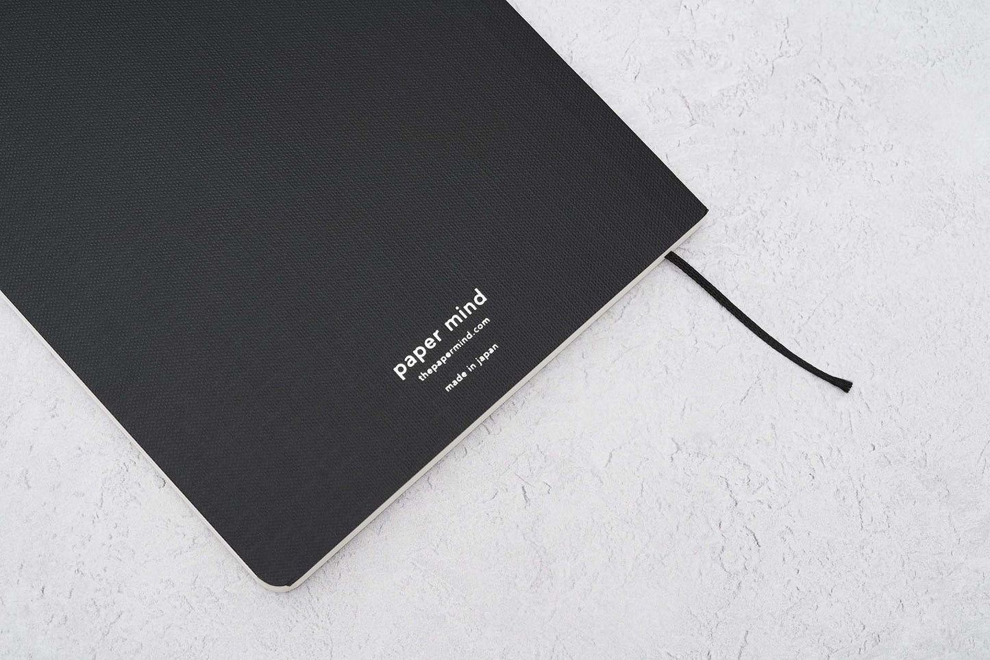 Paper Mind Mitsubishi Bank Paper Notebook Laying on gray surface at an angle showing silver foil logo