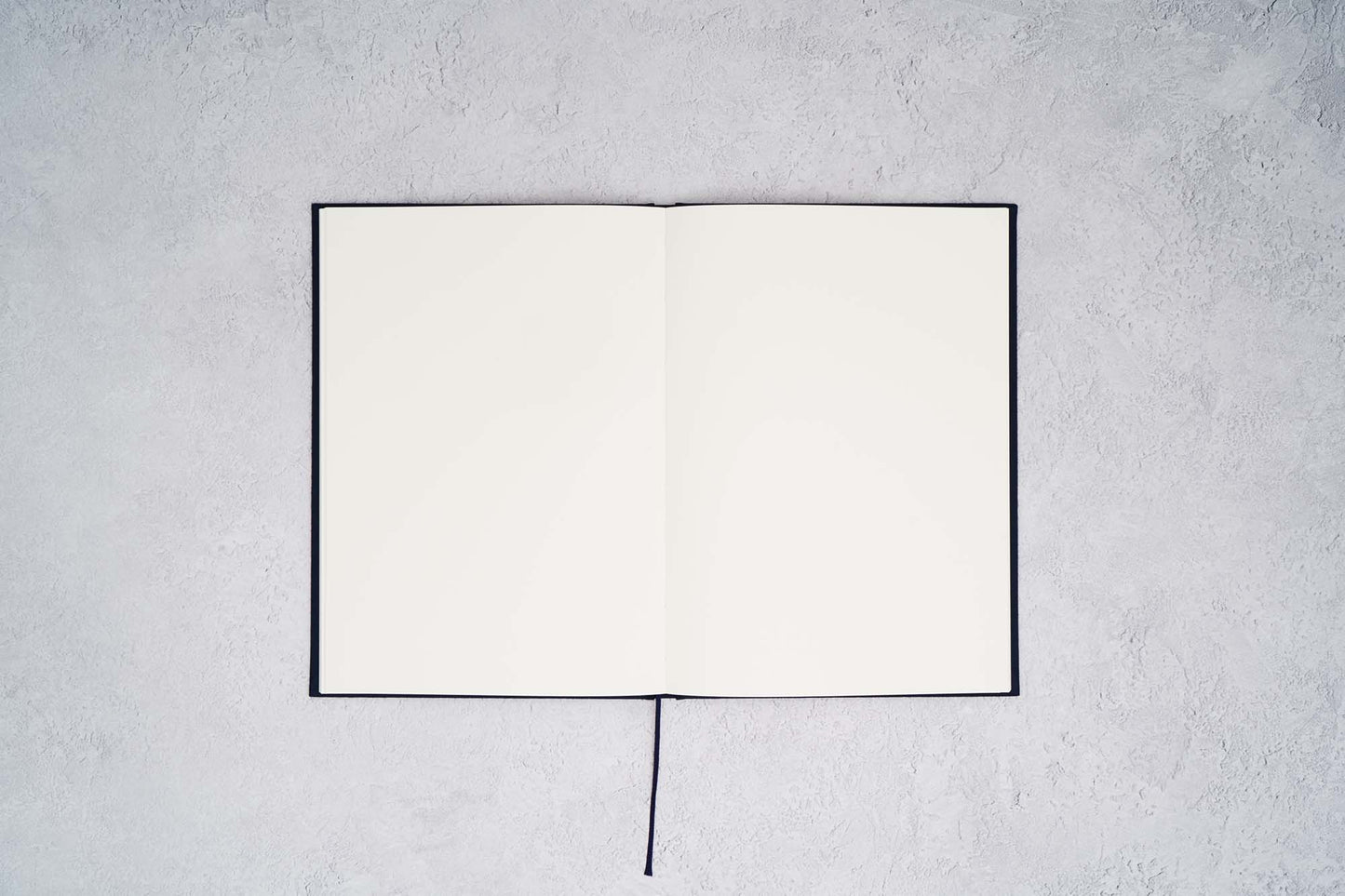 The Paper Mind Cosmo Air Light Hardcover Notebook. Fountain pen friendly Journal. Navy Blue Japanese Linen Cover. Notebook open with blank pages on gray concrete background.