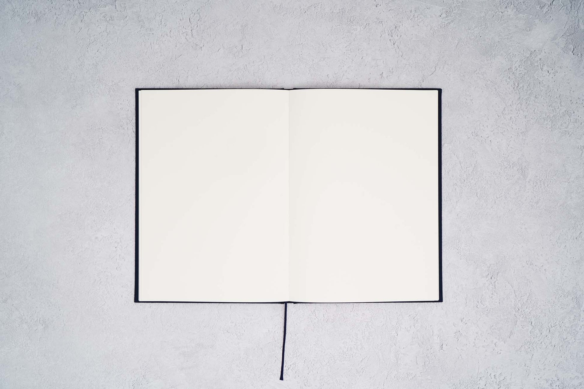 The Paper Mind Cosmo Air Light Hardcover Notebook. Fountain pen friendly Journal. Navy Blue Japanese Linen Cover. Notebook open with blank pages on gray concrete background.